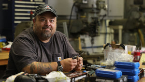 Custom knife designer Mike Wallace sitting at table working on knife designs