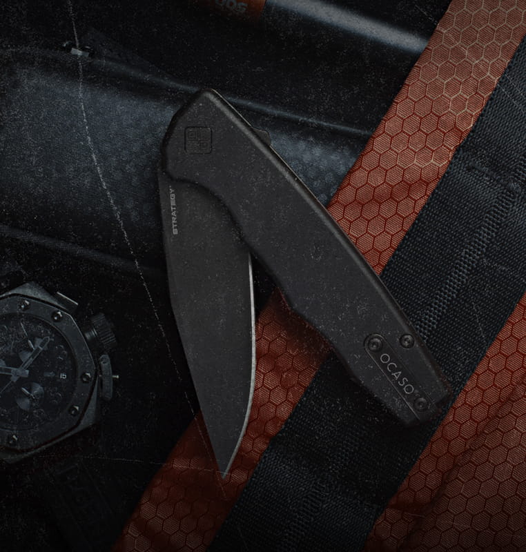 Black folding knife on a textured surface with a watch partially visible